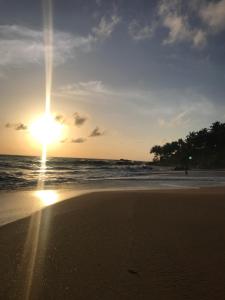 a sunset on a beach with the sun setting at Rob Roy in Beruwala