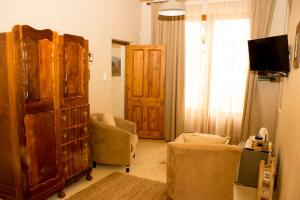 a living room with a large wooden cabinet and chairs at The Ibis Lounge in Nieu-Bethesda