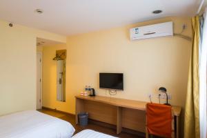 BinhaiにあるHome Inn Tianjin Developmental Districtのベッドルーム1室(壁にテレビとデスク付)