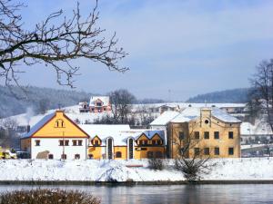 a group of buildings in the snow next to a river at Penzion Paták in Kamýk nad Vltavou