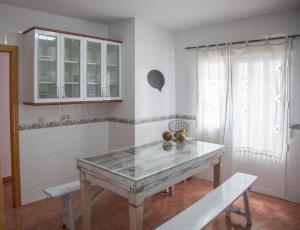 una cocina con mesa y 2 bancos. en Casa Rural Marchena, en Navahermosa