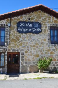 a stone building with a sign on the side of it at Hostal Refugio De Gredos in Navarredonda de Gredos
