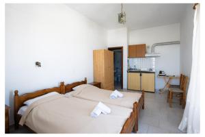a bedroom with two twin beds and a kitchen at kosmas rooms in Skiros