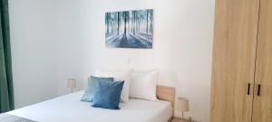 a white bed with blue pillows and a painting on the wall at DaVita in Novalja +14 photos