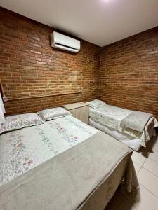 a bedroom with two beds and a brick wall at Casa Praia do Frances in Marechal Deodoro +3 photos