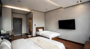 a hotel room with two beds and a flat screen tv at hotel gallery in Pocheon