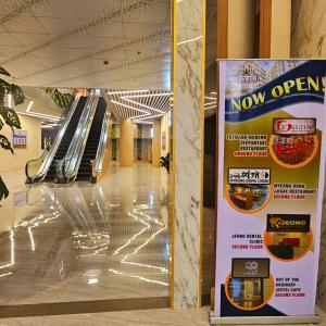 a now open sign in a hallway with an escalator at The ReLuxe Baguio Suite CityHub in Baguio