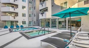 an apartment patio with a pool and chairs and an umbrella at The Sherman Luxe 2 Bed Apt with FREE PARKING in Sherman Oaks Community Hospital Heliport
