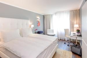 a white bedroom with a large white bed and a desk at Mercure Hotel Raphael Wien in Vienna