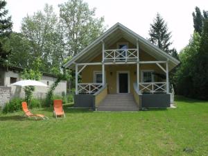 a small yellow house with two chairs and an umbrella at Rozmaring Ház in Balatonlelle