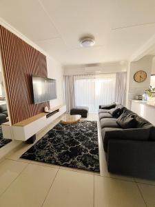 ein Wohnzimmer mit Sofa und Fernseher in der Unterkunft Casa Bliss, Stylish City Escape in Windhoek