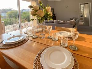 a table with plates and glasses and a vase with flowers at Leighwood Cottage in Paignton +19 photos