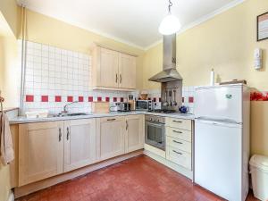 a kitchen with wooden cabinets and a white refrigerator at River Cottage in Two Dales