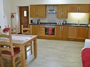 a kitchen with wooden cabinets and a wooden table at Black Thorn Cottage in Falmouth