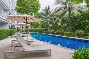 a pool with chairs and an umbrella next to a swimming pool at C222 Cozy 1BR Condo with Pool Access 500 m to Beach in Rawai Beach