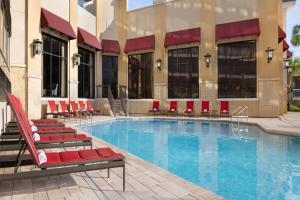 een zwembad met rode stoelen en een gebouw bij Ramada Plaza by Wyndham Orlando Resort & Suites Intl Drive - Newly Renovated! in Orlando