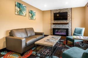 a living room with a leather couch and a fireplace at Quality Inn Janesville North in Janesville