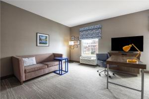 洛根Hampton Inn And Suites Logan, Ut的配有沙发、书桌和电视的客厅