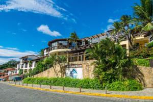 a building on the side of a street with palm trees at Hotel Ilha Branca Inn in Búzios