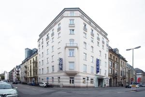 un edificio blanco en una calle de la ciudad con coches aparcados en Hotel Hamburger Hof en Frankfurt
