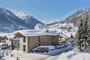 a building with cars parked in a parking lot with snow at Schlosskopf Suiten in Sankt Anton am Arlberg