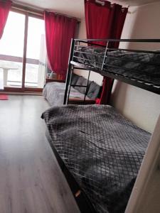 2 Etagenbetten in einem Zimmer mit roten Vorhängen in der Unterkunft Appartement a la Montagne in Villarembert