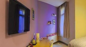 a bedroom with purple walls and a television on the wall at Dalian Household Theme Hotel Huanghe Road Branch in Dalian +120 photos