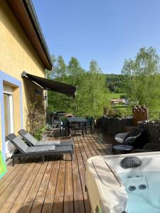 a wooden deck with a table and chairs on it at LA MAISON D'ULYSSE spa et détente in Anould