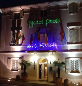 un cartel del portal del hotel en el lateral de un edificio por la noche en Hotel Paola en Altopascio