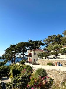 a house on the side of the water with flowers at Rooms Lemonakia Beach in Kokkari