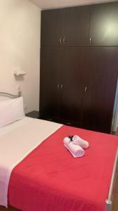 a bed with two pink slippers on a red blanket at Rooms Lemonakia Beach in Kokkari