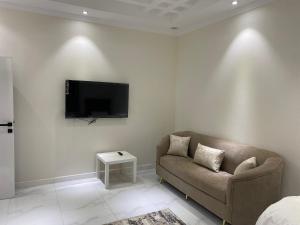 a living room with a couch and a tv on a wall at شقق الضباب 2 in Al Baha