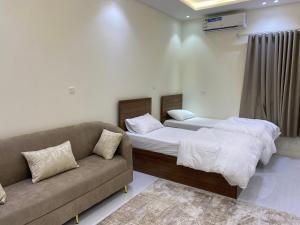 a bedroom with two beds and a couch in it at شقق الضباب 2 in Al Baha