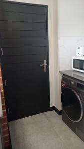 Una puerta negra en una cocina con lavadora. en Lifestyle Apartment, en Midrand