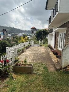 a fence next to a house with some plants at Athens Nuwara Eliya Villa in Nuwara Eliya