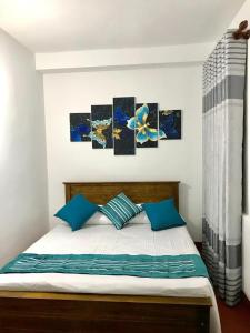 a bedroom with a bed with four paintings on the wall at Athens Nuwara Eliya Villa in Nuwara Eliya +6 photos