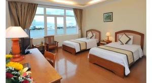 a hotel room with two beds and a table with flowers at Bamboo Green Hotel in Da Nang +57 photos