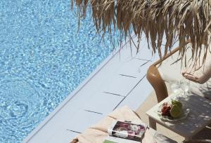 Una mesa con un plato de comida junto a una piscina. en Apsenti couples only, en Agios Ioannis Mykonos