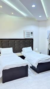 a bedroom with two beds with white sheets at شاليهات ووحدات فندقية وشقق مفروشة بالباحة - العقيق in Al ‘Aqīq