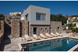 a villa with a swimming pool and lounge chairs at Villa Hermione in Agios Nikolaos