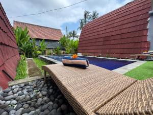 Un banco de mimbre con una flor al lado de un edificio. en Villa Mantra Ubud, en Ubud
