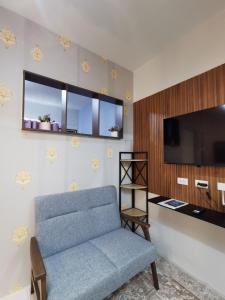 a living room with a blue chair and a flat screen tv at Coastal Stay at Oceancrest in Cebu City