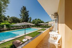 a balcony with a pool and chairs and an umbrella at Villa-Toula in Roda