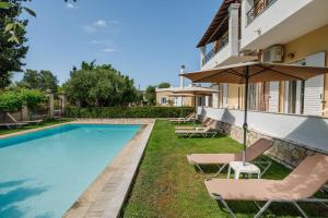 a pool with chairs and an umbrella next to a house at Villa-Toula in Roda