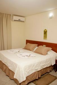 Un dormitorio con una gran cama blanca con flores. en Hotel Midas en Cornélio Procópio
