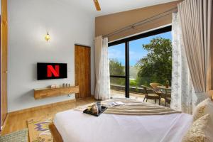 a bedroom with a bed and a large window at SaffronStays Miorah in Bhowāli