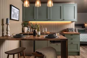 a kitchen with a wooden table with plates and wine glasses at Rabbits Warren - Cotswolds Stay with Sauna and Hot Tub in Hankerton