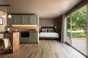 a bedroom with a bed and a kitchen with a window at Rabbits Warren - Cotswolds Stay with Sauna and Hot Tub in Hankerton