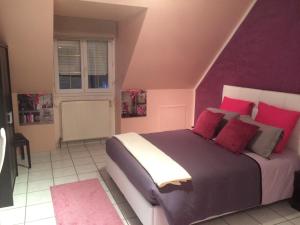 a bedroom with a bed with purple walls and red pillows at L'Eden Orly Aéroport in Thiais