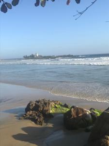 a beach with rocks in the sand and the ocean at Namastay Homes in Kovalam +2 photos